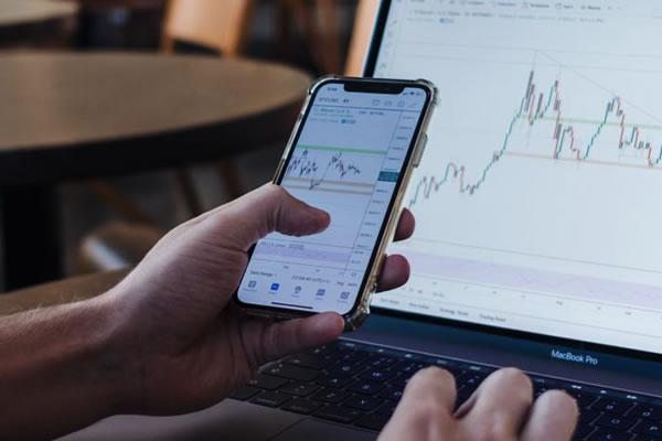 trader tracking market performance on phone and computer